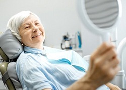 elderly woman looking at her smile in the mirror