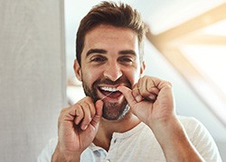 Man smiling while flossing at home