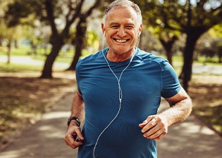 Senior man smiling while jogging outside