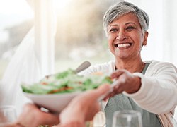 Smiling woman grabbing salad bowl across the table