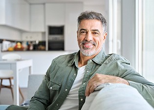 Senior man smiling while sitting on couch