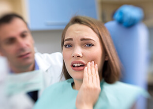 Young woman in pain holding cheek