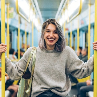 person smiling and standing on subway