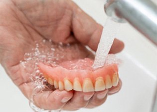 Person rinsing off their dentures