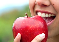 Closeup of patient with dental implants in Marlton eating an apple