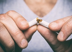 Closeup of patient with dental implants in Marlton breaking a cigarette