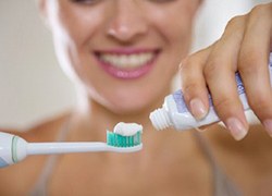 woman putting toothpaste on an electric toothbrush