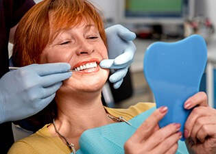 older woman admiring her smile in the mirror