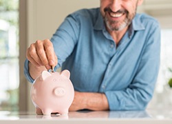 dman putting coins into a pink piggy bank