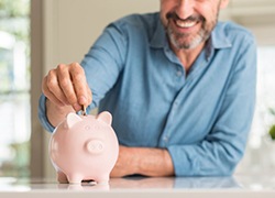 dman putting coins into a pink piggy bank 