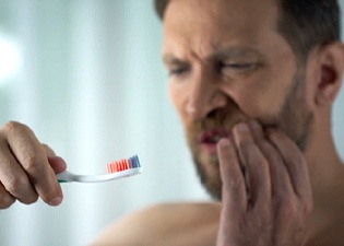 Man holding a toothbrush with blood on it