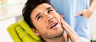 Male patient in pain holding his cheek