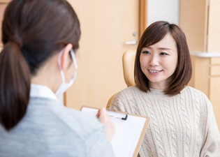 A young female meeting with her dentist to discuss her eligibility for Snap-On Smile treatment in Marlton