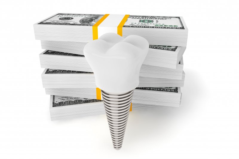 Close-up of dental implant in front of a stack of money