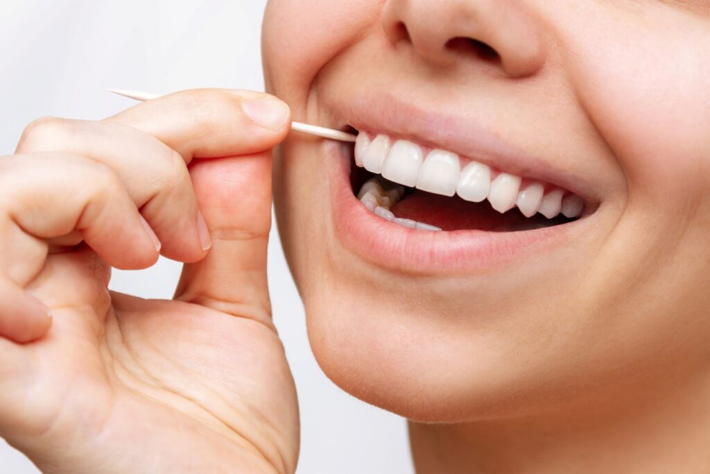 Nose-to-chin view of woman using toothpick on her teeth