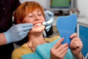 Woman admiring dentures in the dentist's chair.